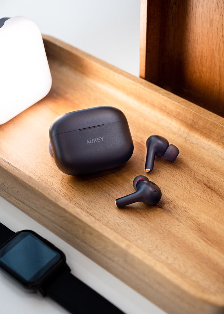 A Black Aukey Wireless Earbuds and Case on Brown Wooden Surface